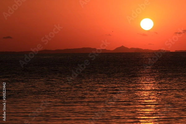 Fototapeta 夕焼けで橙に染まる空と穏やかな海