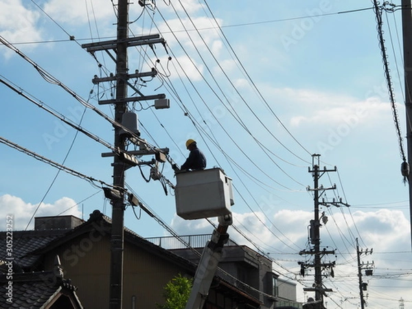 Fototapeta 高所作業車のゴンドラに乗って電線の補修を行う作業員