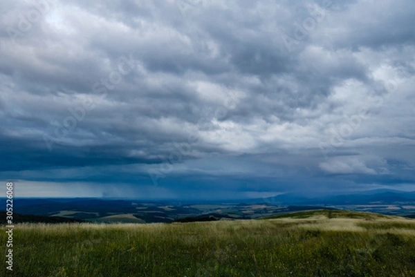Fototapeta A meadow on top of a hill under a stormy sky