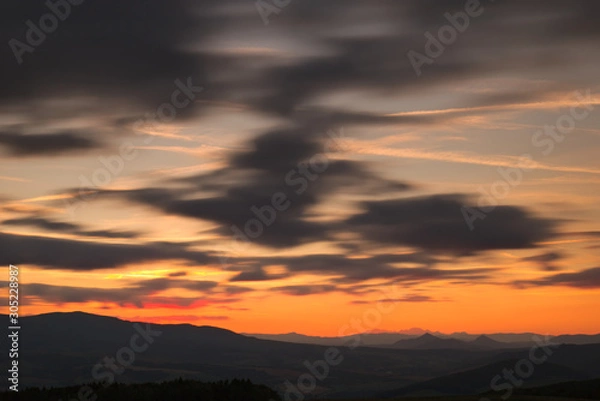 Fototapeta Red sunset with cloudy sky and mountains in the background