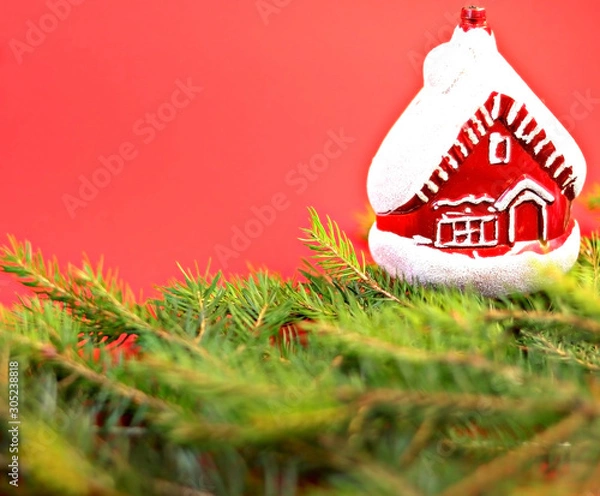 Obraz Christmas composition Christmas decorations, toy in the form of a house, fir branches with a red background. Flat design, side view, copy space. Place for text.