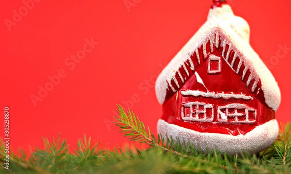 Obraz Christmas composition Christmas decorations, toy in the form of a house, fir branches with a red background. Flat design, side view, copy space. Place for text.