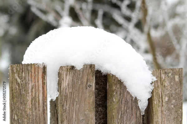 Fototapeta old wooden fence covered with a white snowdrift on a winter background, seasonal, weather, first snowfall concept, horizontal, close-up