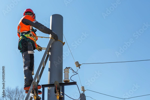 Fototapeta Working electrician tied to the pole with a safety rope