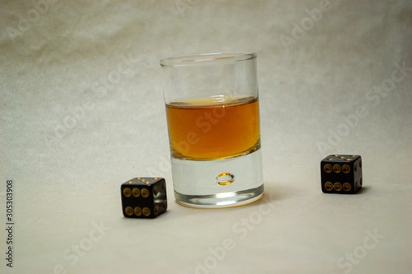 Fototapeta Glass with cognac on a light background with dices