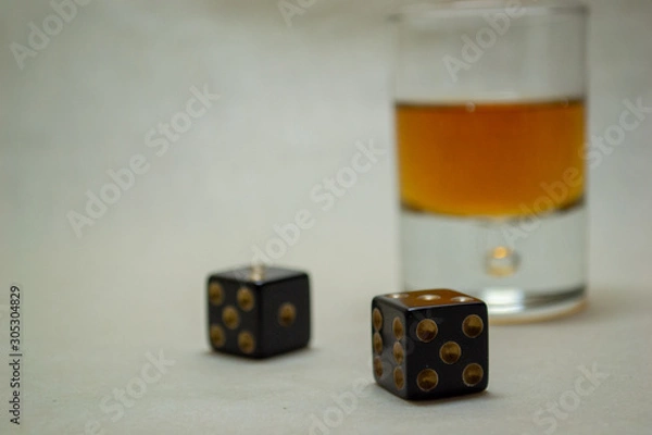Fototapeta Glass with cognac on a light background with dices