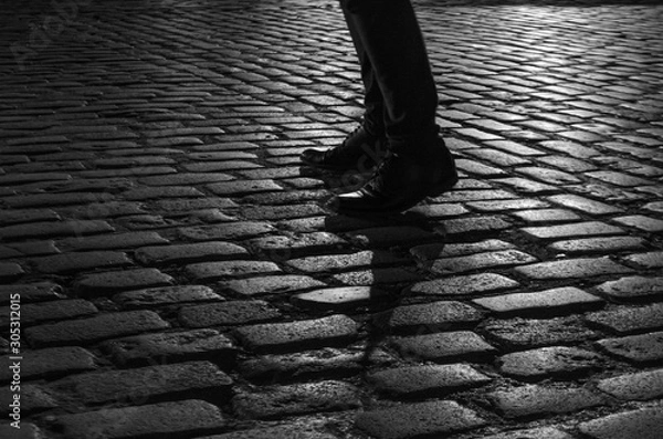 Fototapeta silhouette of a person's shoes while walking on the cobblestone
