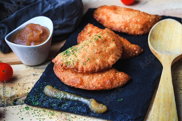 Fototapeta Four small pasty homemade with applesauce on slate plate. Front view, no people. Food concept