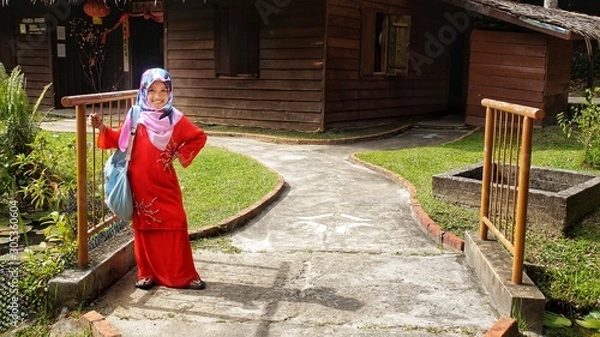 Obraz Portrait of young girl wearing traditional dress 'baju kurung' with hijab. Selected focus. Image contain certain grain or noise and soft focus when view at full resolution.
