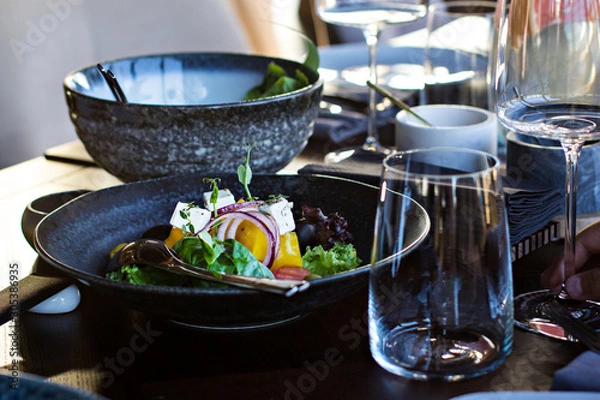 Obraz greek salad in a dark plate on the table