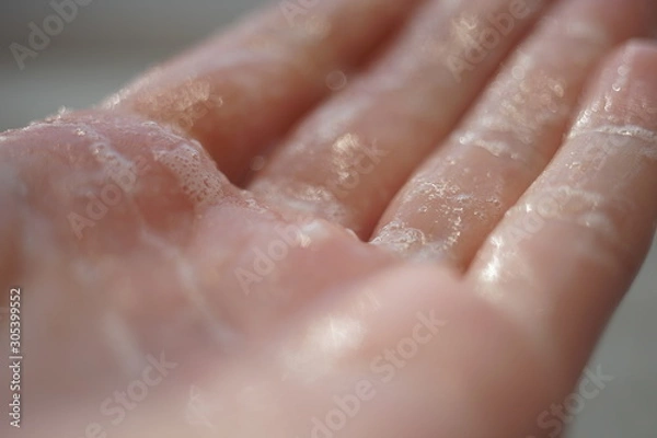Fototapeta Wet hand with soap foam, macro photo.