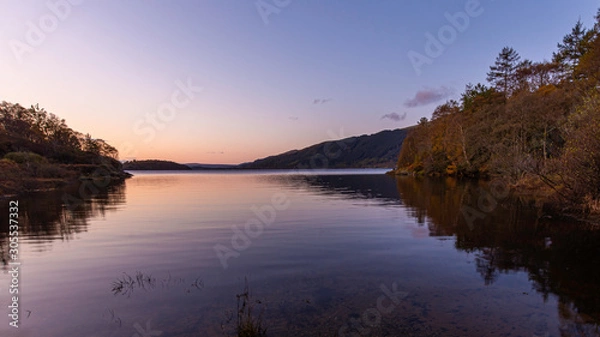 Fototapeta Sunrise at Loch Lomond, Scotland,UK..Beautiful landscape of Scottish Highlands.Tranquil morning scene with reflection of autumn coloured trees in calm lake surface.