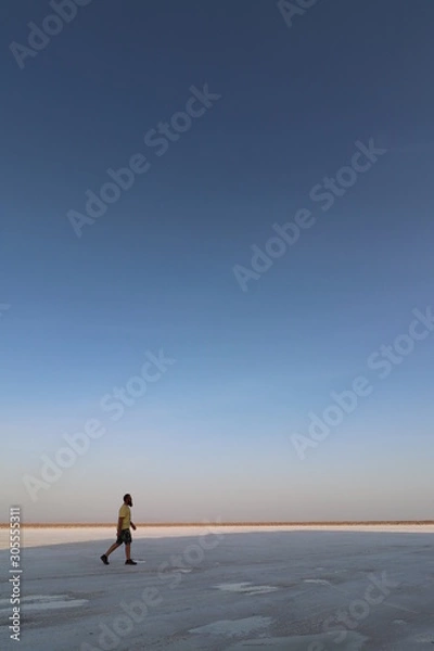 Fototapeta Man running through the desert/on a beach at sunset