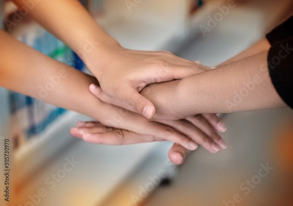 Fototapeta In selective focus of human hands stacked togethersign and symbol of togetherness,the collaboration,unity,blurry light around