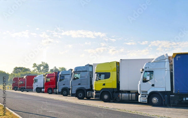 Fototapeta Various types of trucks in the parking lot next to the motorway.