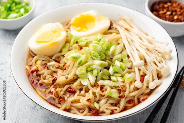 Fototapeta Asian soup ramen with noodles, spring onion, enoki mushrooms and boiled egg in bowl on concrete background. Selective focus.
