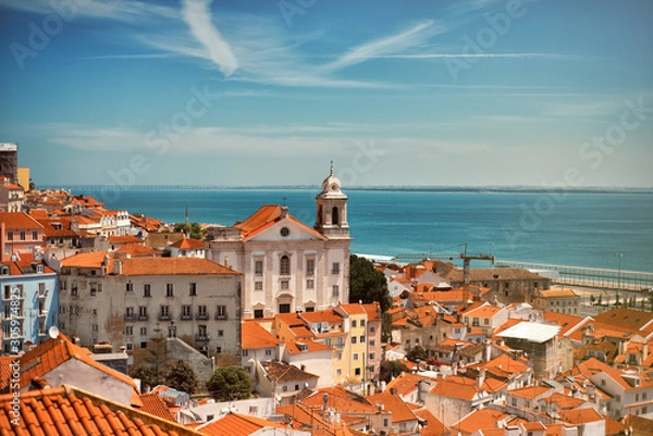 Obraz Panoramic view on the roofs of Lisbon from Alfama in the summer time with blue sky and river on background. Touristic