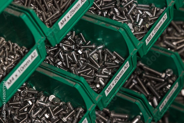 Obraz Hundereds of bolts and nuts of various shapes and sizes in green tubs located in a london factory. Used for industrial and commercial production shiny new hardware.