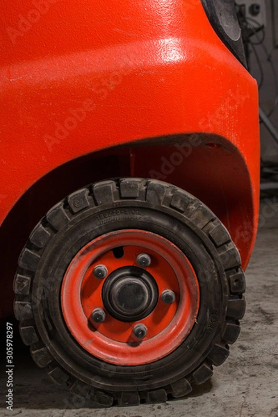 Obraz Red dirty forklift wheel in a factory with dirty tyres and dirty nuts and bolts. Vivid bright colours and dirty tyres. Covered in dust and grime