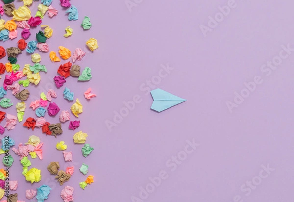 Fototapeta A paper plane flies away from crumpled multi-colored stickers. Leadership skills. Successful business choice concept.