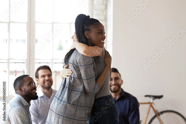 Fototapeta Happy african american manager hugging smiling female colleague.