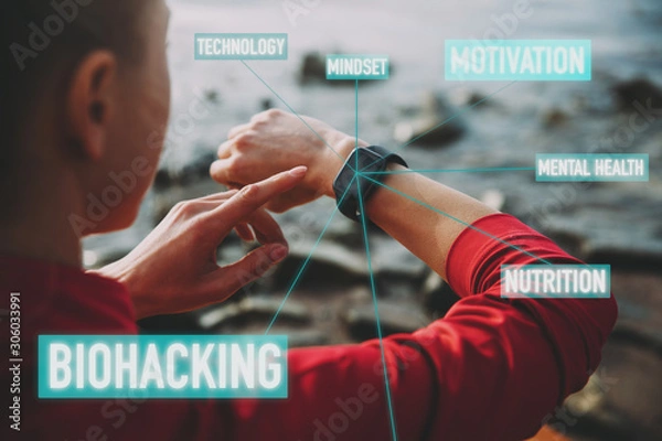 Fototapeta Concept of Biohacking, Modern Technology in Health and Sports. Woman Uses a Smartwatch on Her Hand to Train Healthy Lifestyle, View from behind