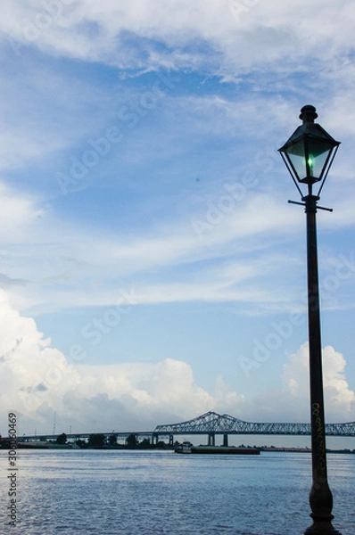 Fototapeta Streetlamp and Bridge Silhouetted Against Mississippi River with Cloudscape