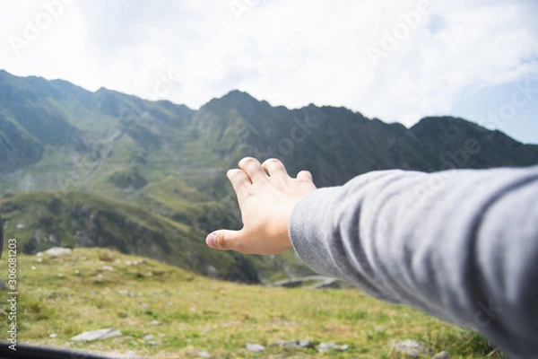 Fototapeta Hand of tourist straining after big green mountains