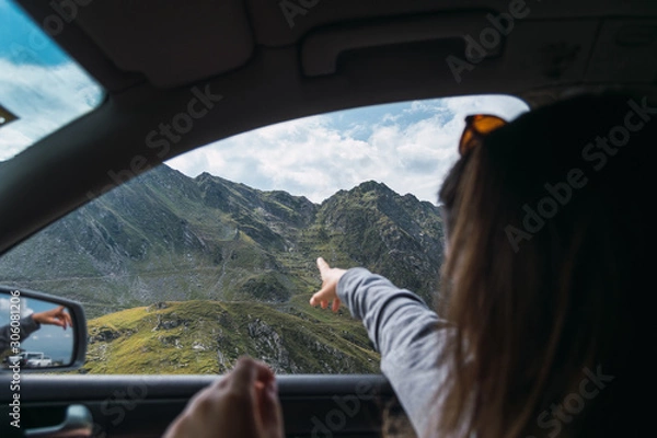 Fototapeta Resting anonymous lady showing on mountains from car