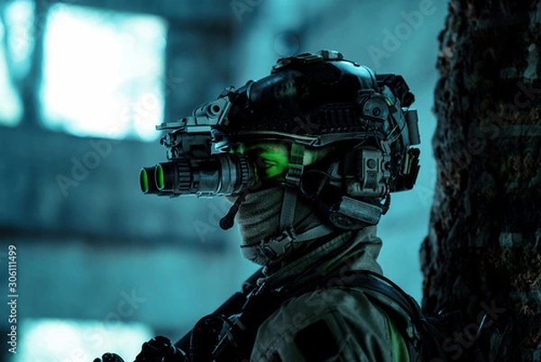 Fototapeta Closeup man uniform with machine gun and turned on night vision device. Airsoft soldier with green light on face in night building. Side view