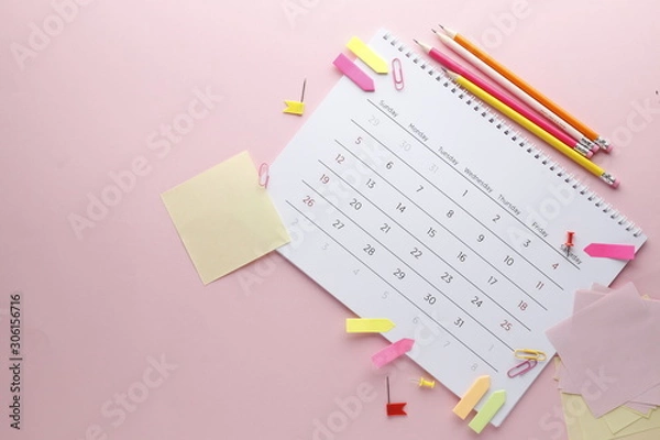Fototapeta Planning calendar on a pink background with pins, pencils, stickers .. Important date. Place for text. Planning concept.
