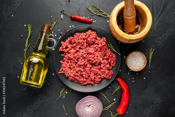 Fototapeta Fresh raw minced beef with herbs and spices on a black plate on a stone background