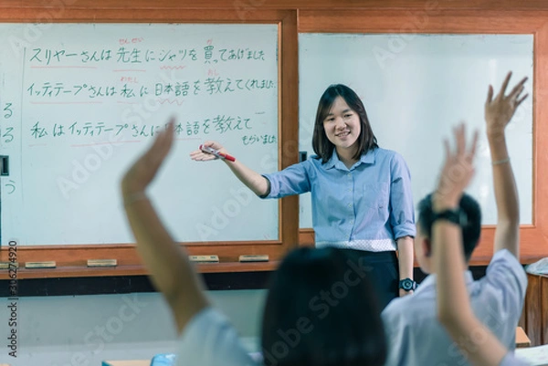 Fototapeta An Asian female teacher is teaching Japanese. The meaning of texts are "Mr. Suriya bought a shirt for the teacher, Mr Ittithep taught me Japanese, I have been taught Japanese from Mr Athithep".