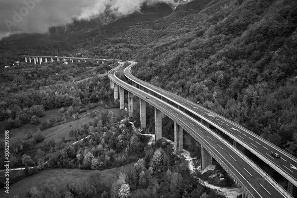Fototapeta black and withe photo of alpine speed road in Italia. Aerial view from above with clouds on the background