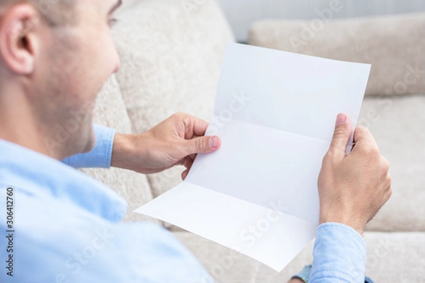Fototapeta Man reading a letter at the couch, men's hands, close up, rear view, copy space, toned