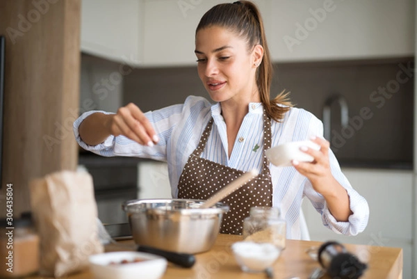 Fototapeta Young woman in kitchen preparing lunch