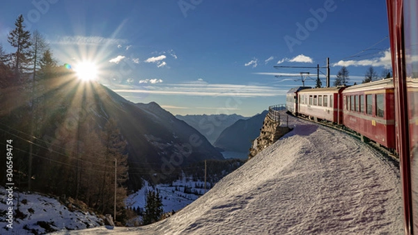 Fototapeta le train rouge glacier express traverse des paysages enneigés au soleil en suisse