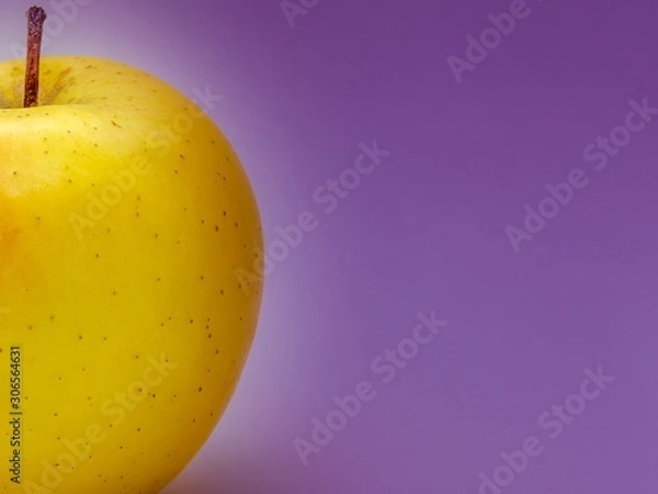 Fototapeta Yellow apple on a purple background with meta under the text