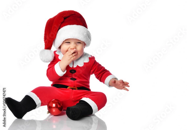 Fototapeta Little child boy toddler in santa claus christmas costume and hat happy smiling ready to celebrate new year party