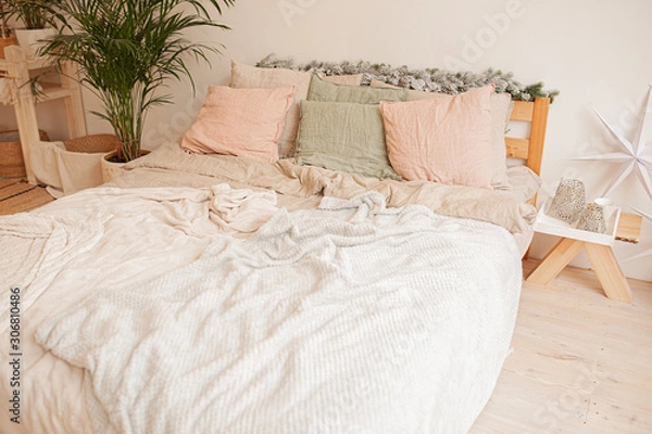 Fototapeta cozy large bright bed, with a rumpled fluffy white plaid, pink and green pillows