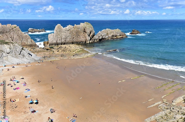 Obraz Tourists enjoying the sun in the beach of Playa De La Arnia on a sunny day, Santander. Cantabria, Spain
