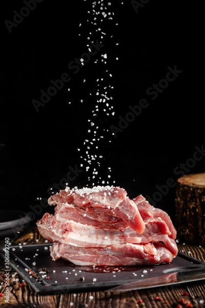 Obraz Raw pork meat lies on a cutting board, on a wooden table, next to a kitchen knife. Pickled meat in spices. Background image.