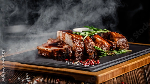 Fototapeta American food concept. Grilled pork ribs with grilled sauce, with smoke, spices and rosemary. Background image. copy space