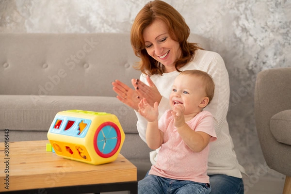 Fototapeta Happy grandmother with baby granddaughter is playing with sorter. Learning, gross and fine motor skills, mothers day, grandparents day concept