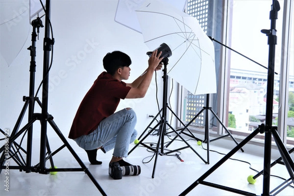 Obraz Young photographer adjust light in modern studio background
