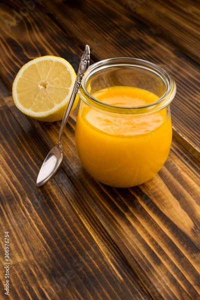 Fototapeta Lemon kurd in the glass jar on the brown wooden background. Location vertical. Copy space.