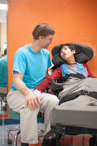 Obraz Disabled little boy in wheelchair talking with father in hospital room