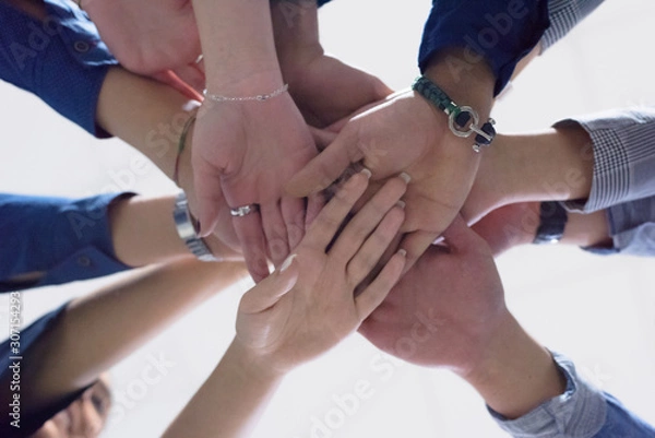 Fototapeta College Students Teamwork Stacking Hand Concept. Close up of young people putting their hands together. Friends with stack of hands showing unity and teamwork.