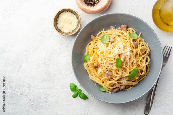 Fototapeta Klasyczny makaron spaghetti carbonara z pancettą, żółtkiem i parmezanem na betonowym tle. Widok z góry, miejsce na kopię.