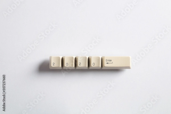 Fototapeta Computer keyboard keys with 2020 enter written using the white buttons on a dark background. Holiday technology concept. New year 2020 card.